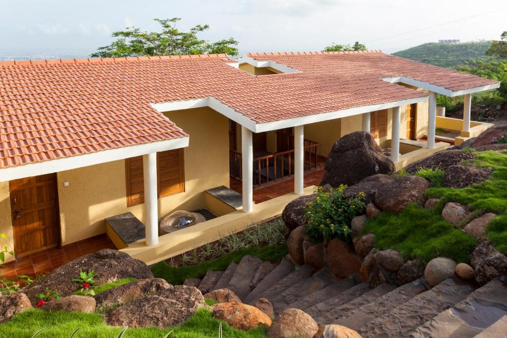 a house with a tile roof and a rock garden at Nisarg Resort in Kolhapur