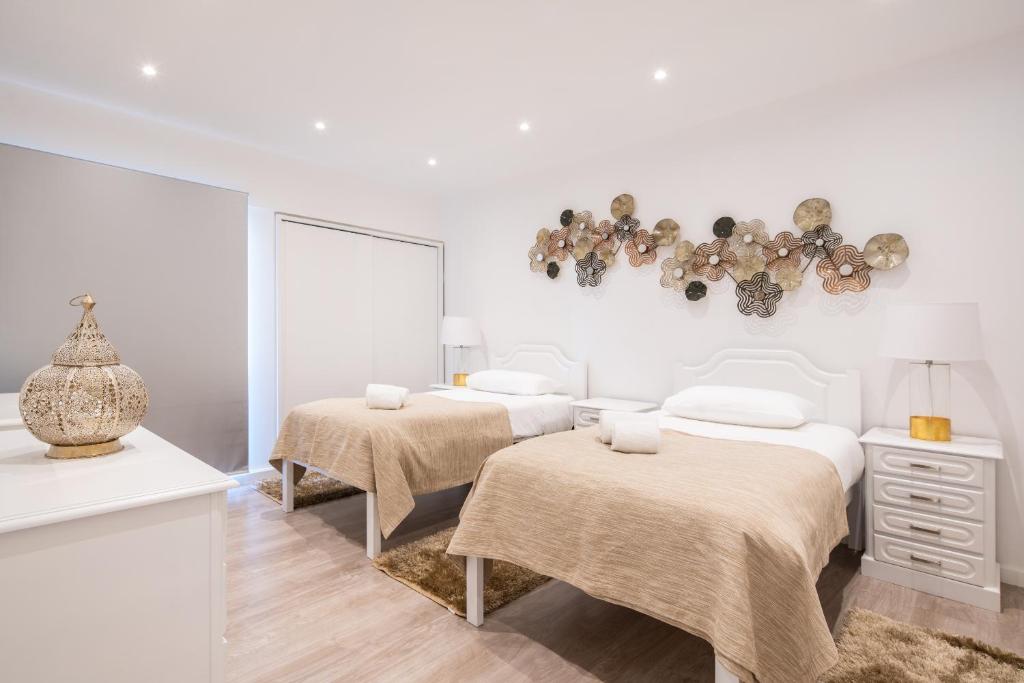 a white bedroom with two beds and a chandelier at Piornais Apartment by HR Madeira in Funchal