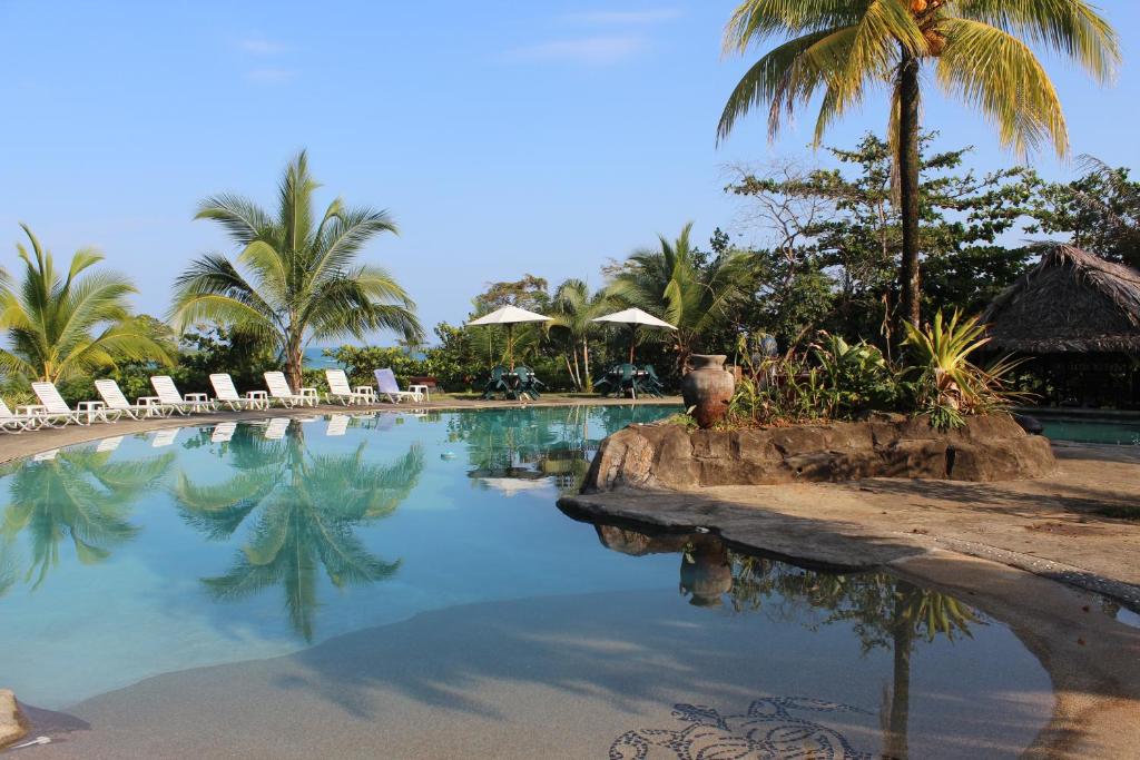 a swimming pool with chairs and palm trees at Popa Paradise Beach Resort in Buena Vista