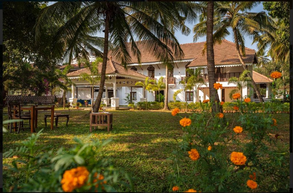 a house with palm trees and flowers in front of it at The Postcard Cuelim, Goa in Cansaulim