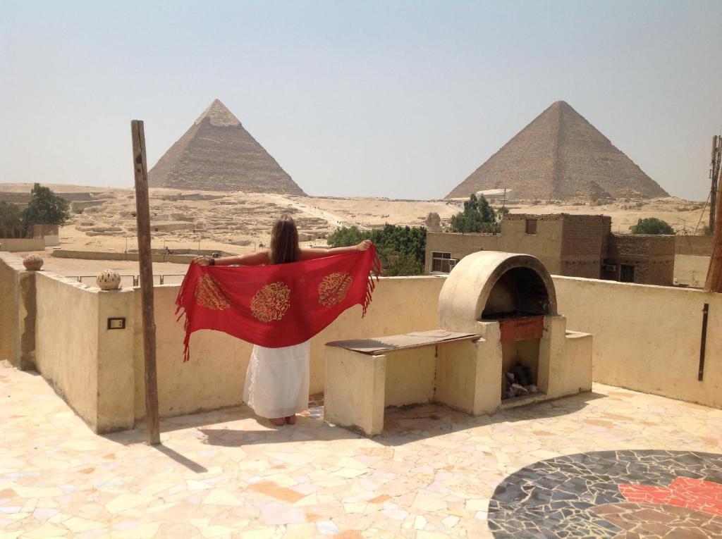a woman standing on a roof looking at the pyramids at Thomas' in Cairo