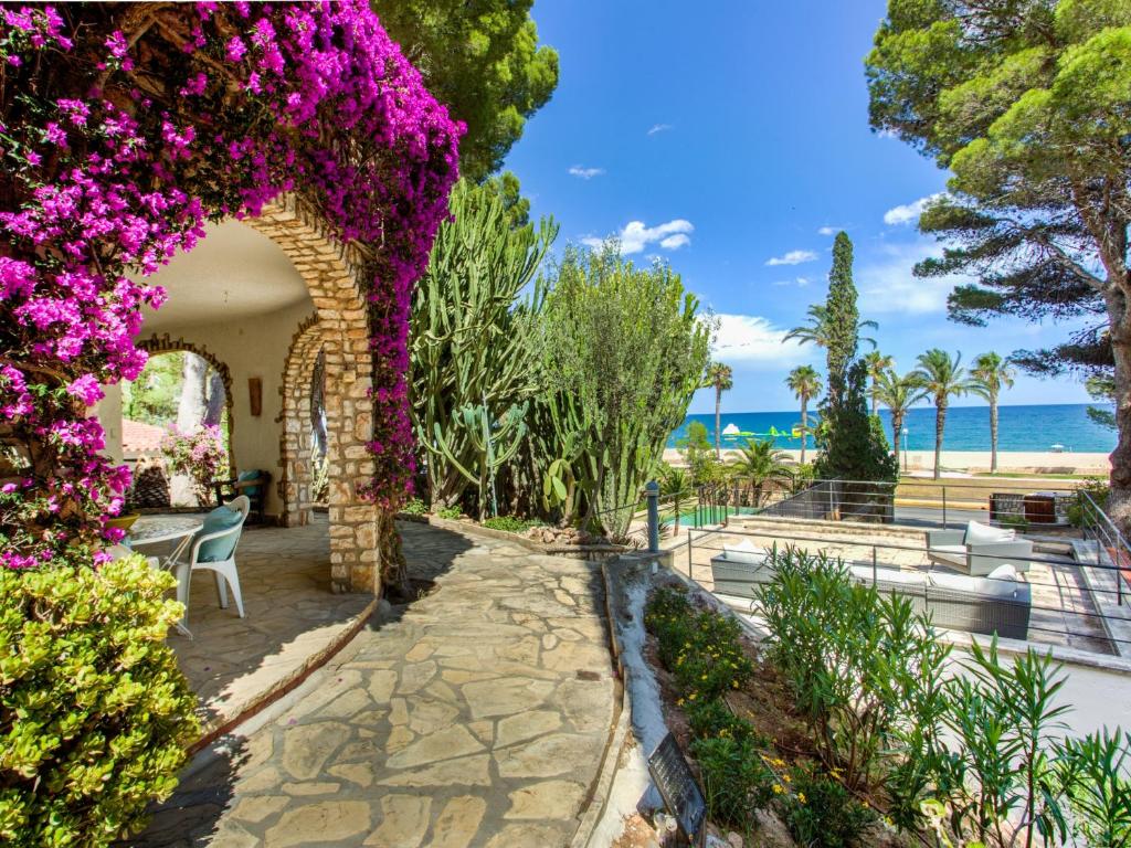 a garden with purple flowers and the ocean in the background at TarracoHomes, Villa with Botanic Garden and Private Pool facing the Beach in Miami Platja