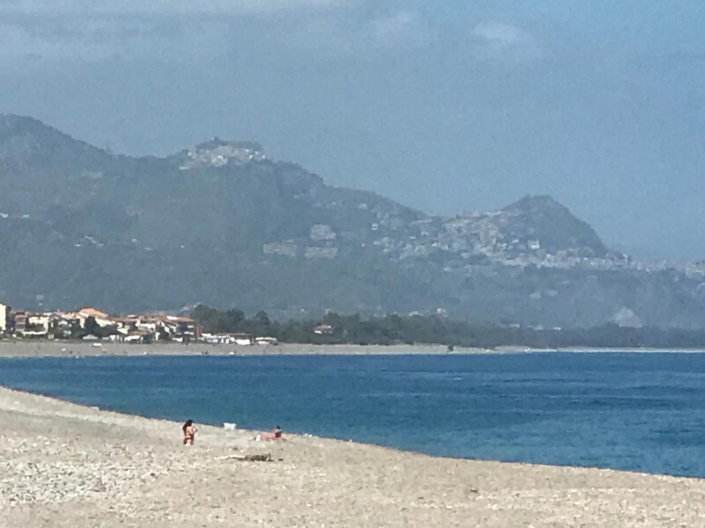 a group of people on a beach with mountains in the background at Casa Vacanze Samira in Fondachello