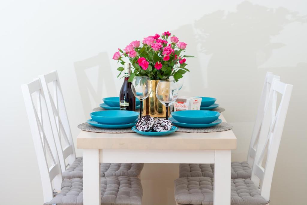 a table with blue dishes and a vase of pink flowers at Apartament Optima in Ustrzyki Dolne