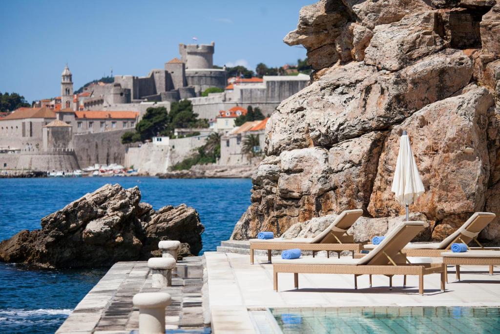 eine Gruppe von Liegen und Stühlen neben dem Wasser in der Unterkunft Grand Villa Argentina in Dubrovnik