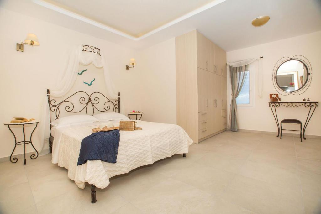 a white bedroom with a large bed and a mirror at Pithos Apartments in Vóthon