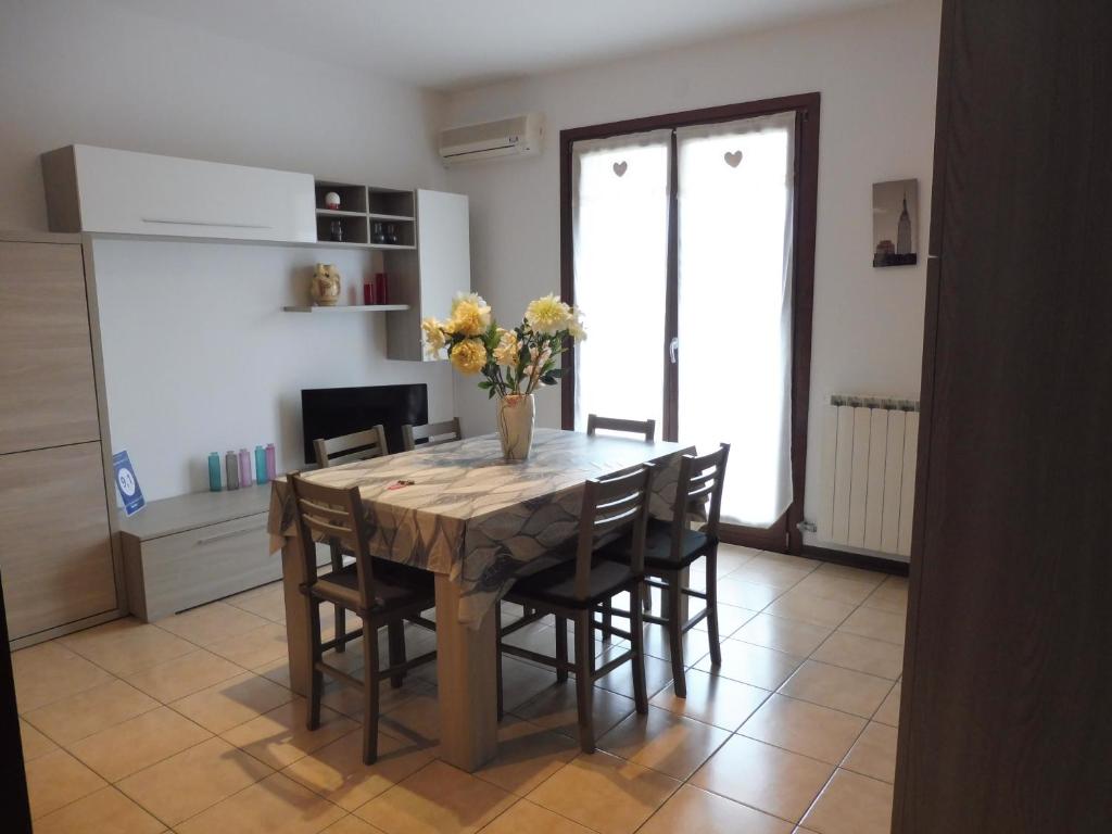 a dining room table with chairs and a vase of flowers at Villaggio Laguna app.to 5 e 38 in Caorle