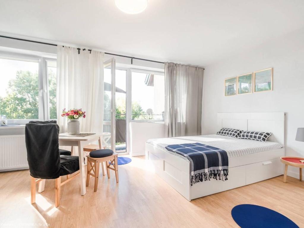 a white bedroom with a bed and a table and chairs at Dom przy borowinie in Kołobrzeg