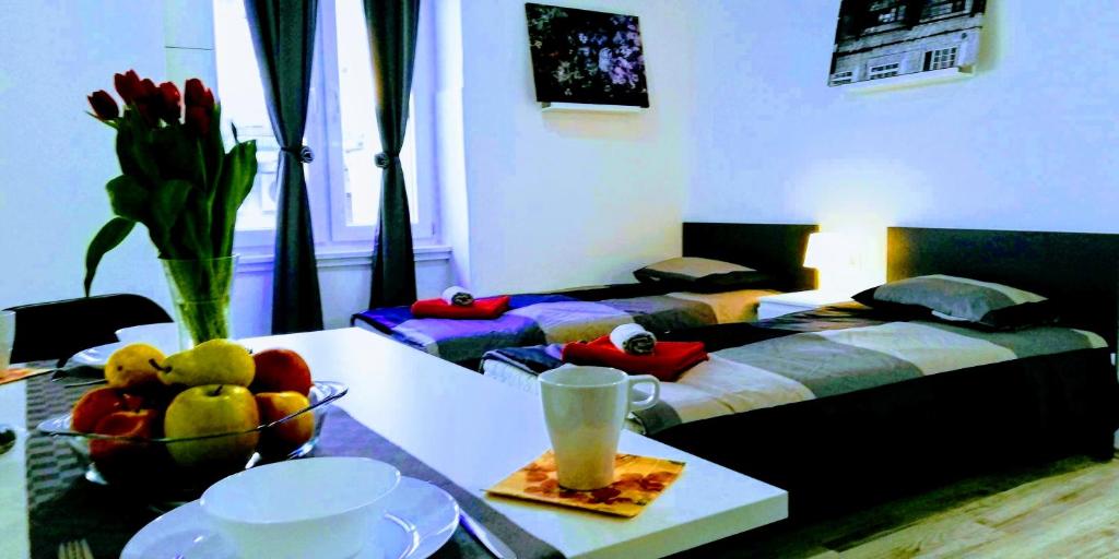 Pokój z 2 łóżkami i stołem z misą owoców w obiekcie Pula Center Apartments and Rooms w Puli