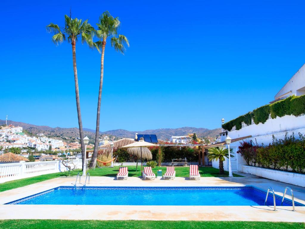 a villa with a swimming pool and palm trees at Villa Tulipan by Interhome in Rincón de la Victoria