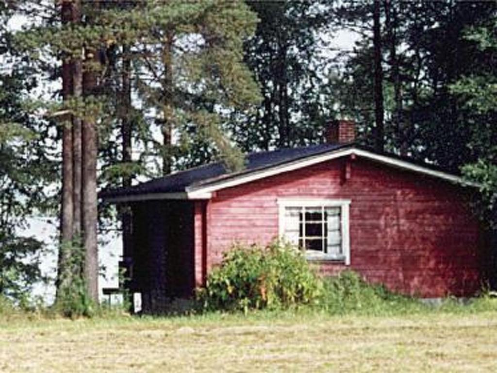 una pequeña casa roja en un campo con árboles en Holiday Home Raanumökki 4 by Interhome, en Lampsijärvi