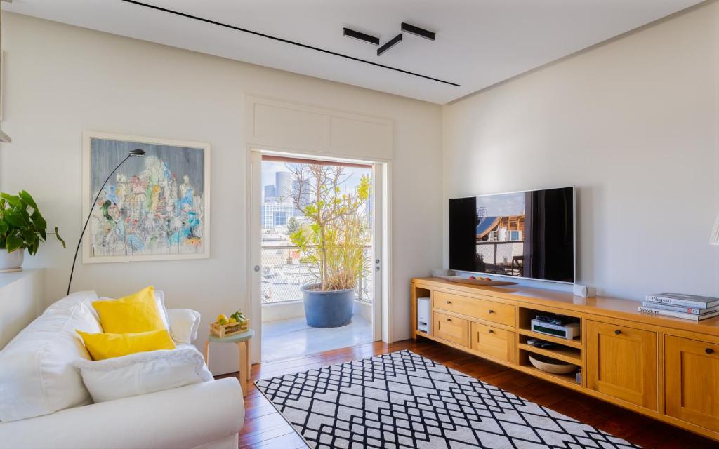 a living room with a white couch and a tv at A luxury Suite in Chen Boulevard in Tel Aviv