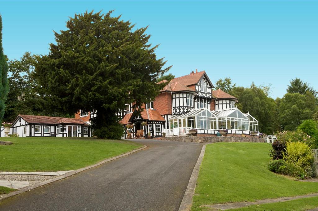 a large house with a road in front of it at Lyons Woodlands Hall in Ruthin