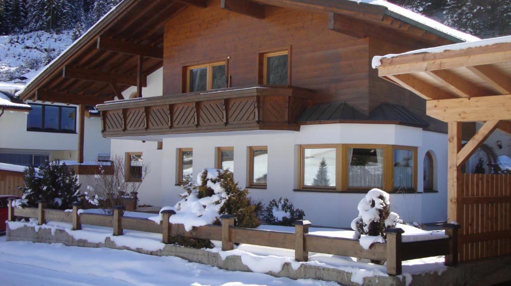 a house with a wooden fence in the snow at Apartments Weißstein in Gries im Sellrain