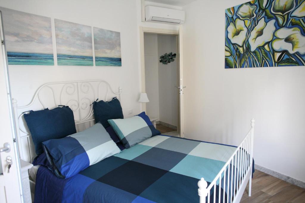 Un dormitorio con una cama azul y blanca y una pintura en B&B Cà di Bollo, en Moneglia