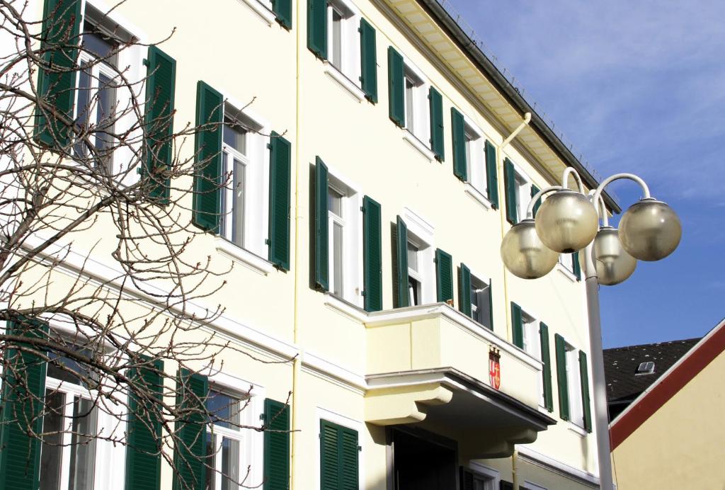 a white building with green windows and a street light at Boutique-Hotel „Altes Rathaus“ in Lahnstein