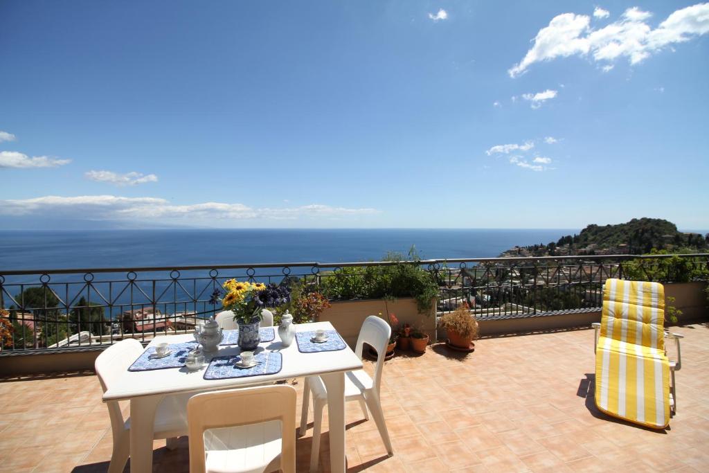 een witte tafel en stoelen op een balkon met uitzicht op de oceaan bij Fontana Vecchia Seaview Apartment in Taormina