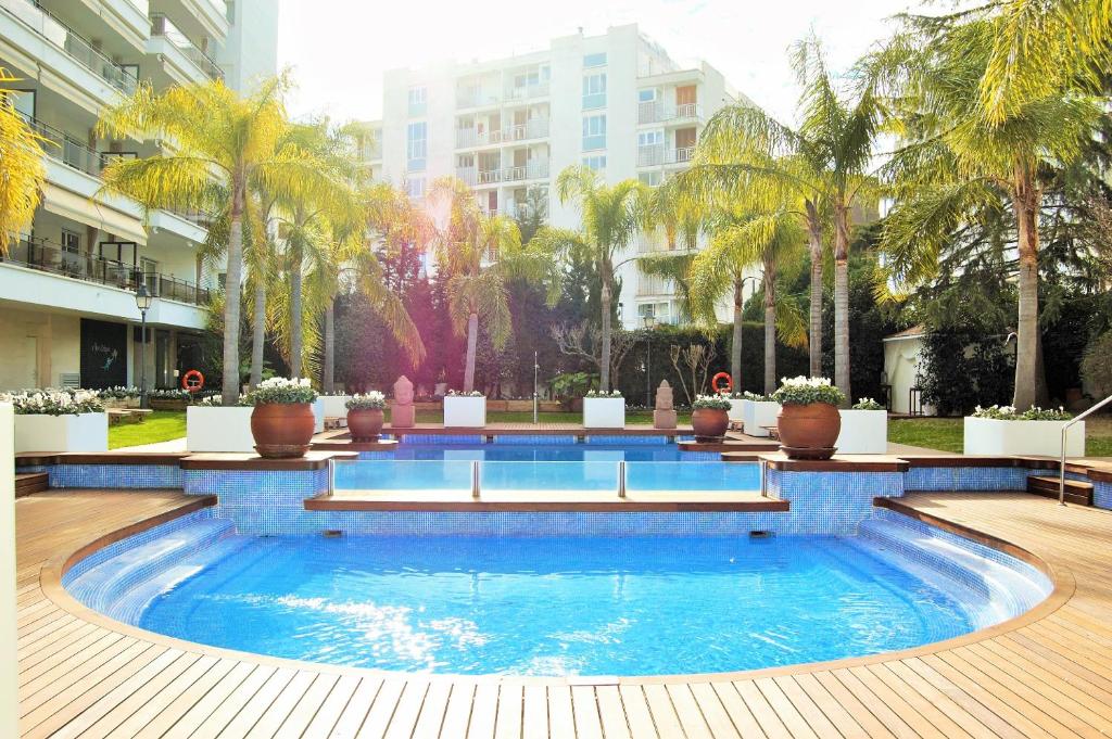una gran piscina con palmeras y edificios en Apartamento Sun Garden Lloret de Mar, en Lloret de Mar