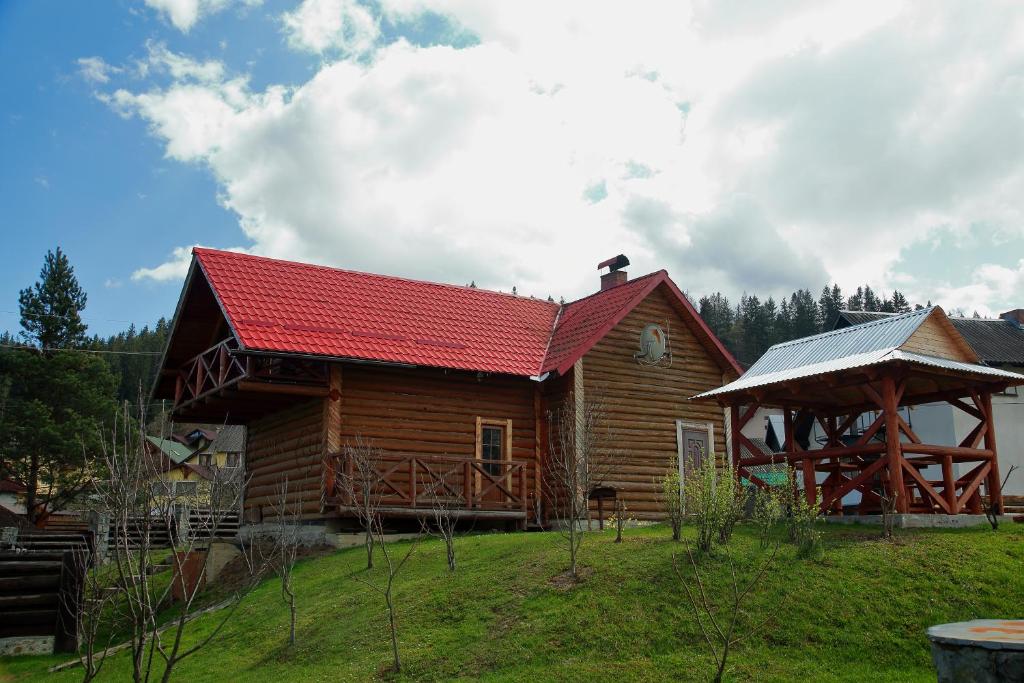ein Blockhaus mit rotem Dach auf einem Feld in der Unterkunft Zatyshna Domivka in Slawske