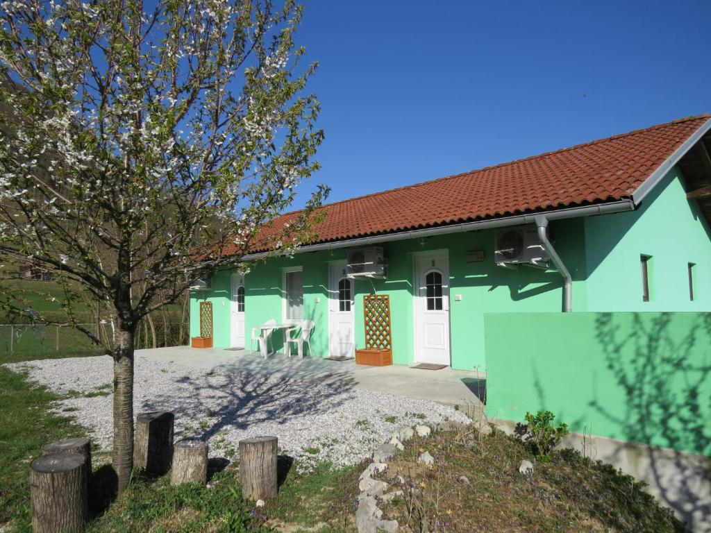 a green house with a tree in front of it at Apartma Patricija - cozy apartments in Tolmin