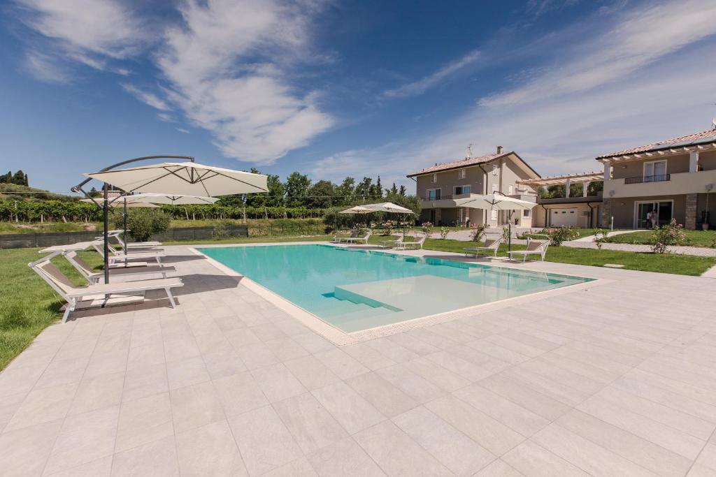 uma piscina com duas cadeiras e um guarda-sol em Luxury Apartment Lazise em Lazise
