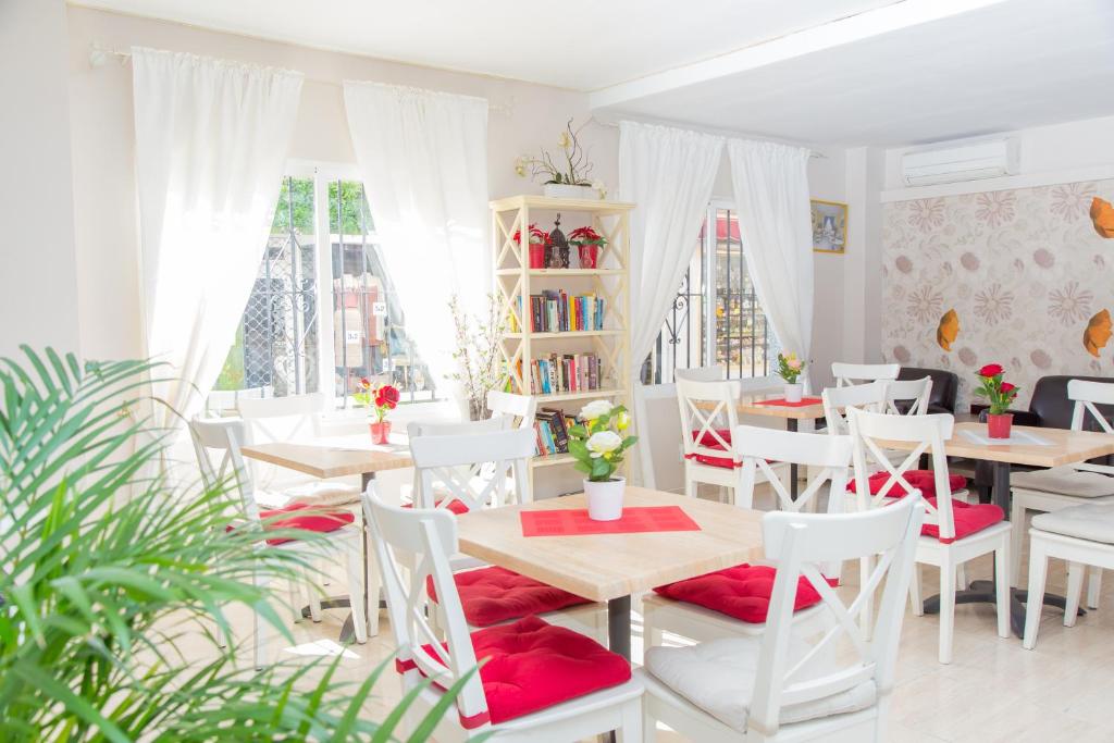 une salle à manger avec des chaises blanches, des tables et des coussins rouges dans l'établissement Hotel Marbella, à Fuengirola