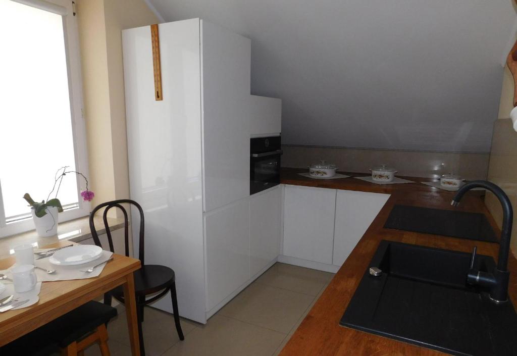 Il comprend une cuisine équipée d'une table et d'un réfrigérateur blanc. dans l'établissement Pokoje gościnne Barka, à Wadowice