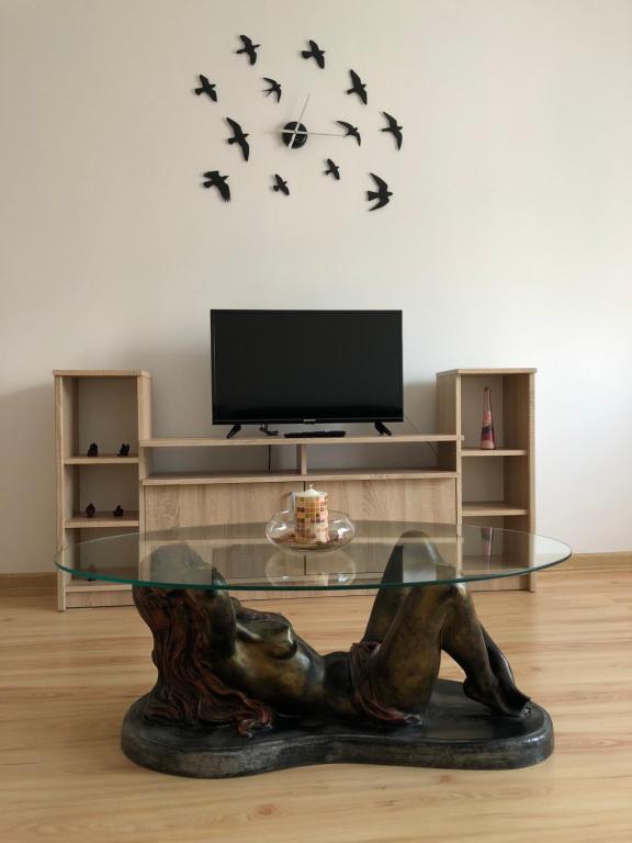 a glass table in a living room with birds on the wall at Apartament Kiseleff in Drobeta-Turnu Severin