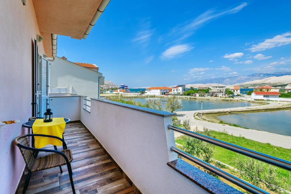 a balcony with a chair and a view of a river at Apartments Rija in Pag