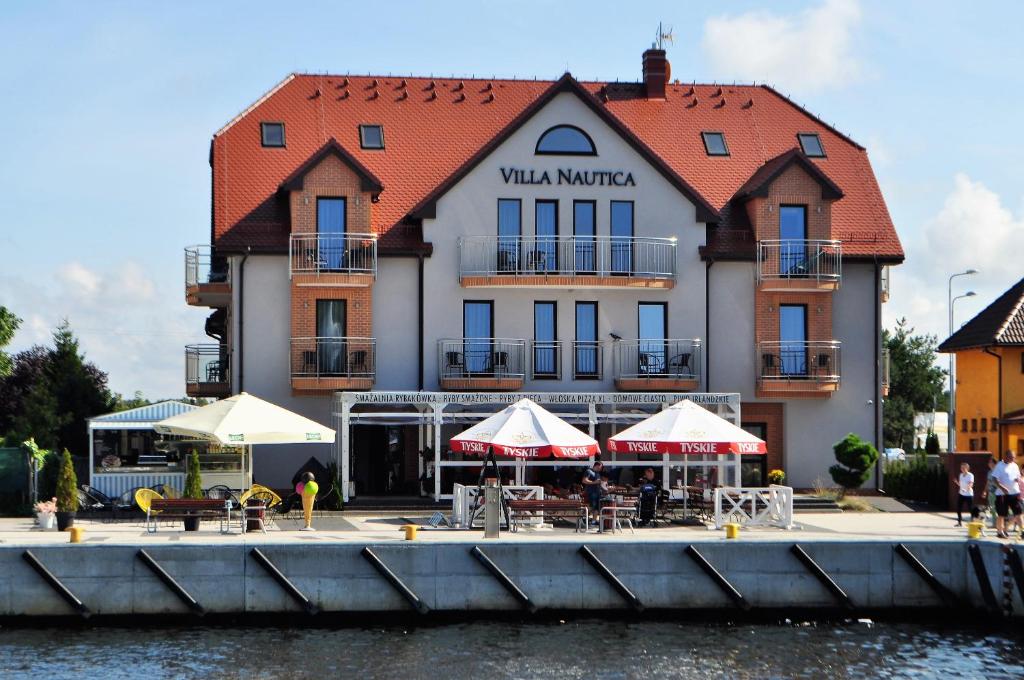 a building with tables and umbrellas next to the water at Villa Nautica in Mrzeżyno