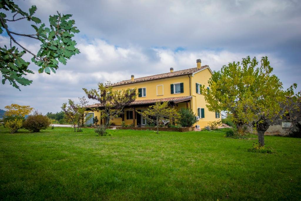 a large yellow house with a green yard at Agriturismo Calamello in Pergola