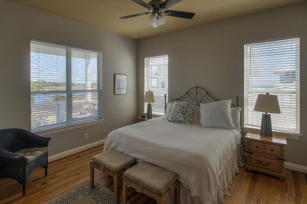 a bedroom with a bed with a ceiling fan and windows at Seaspray in Santa Rosa Beach