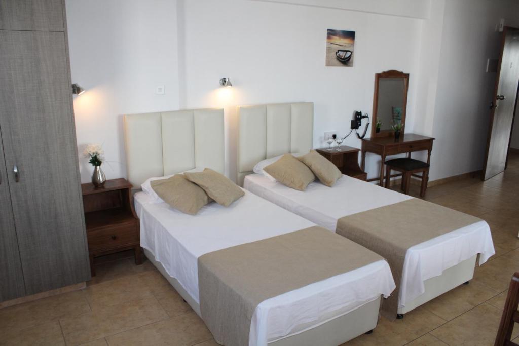 a hotel room with two beds and a table at Maria Zintili Apartments in Ayia Napa