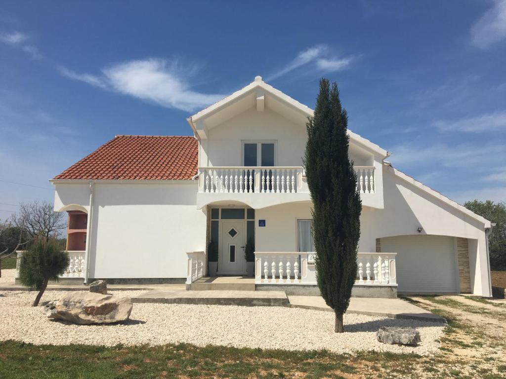 Una casa blanca con un árbol delante. en Villa Zerava Nin en Dračevac Ninski