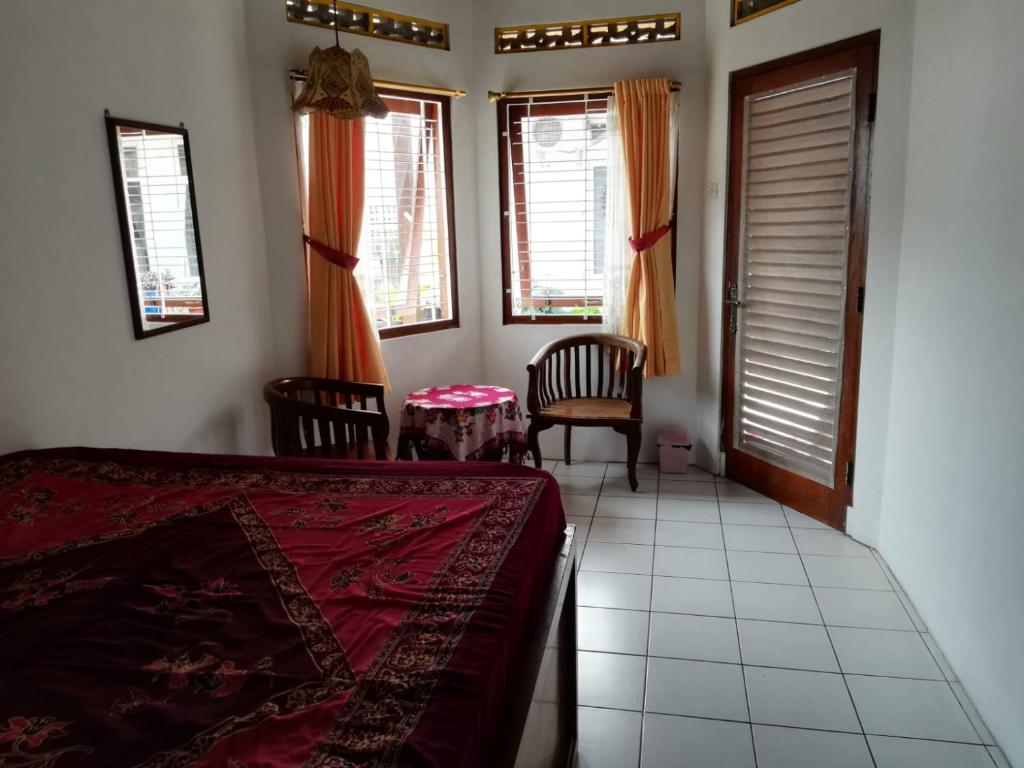 - une chambre avec un lit, 2 chaises et des fenêtres dans l'établissement Lia Homestay, à Yogyakarta