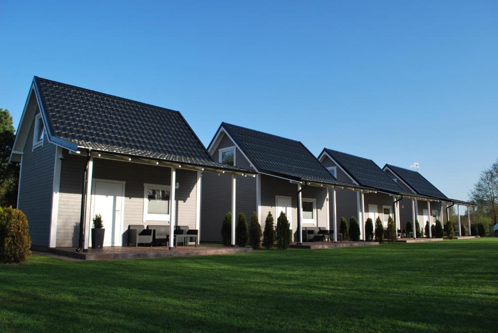 a row of houses with a green lawn at Żurawie domki letniskowe in Kopalino