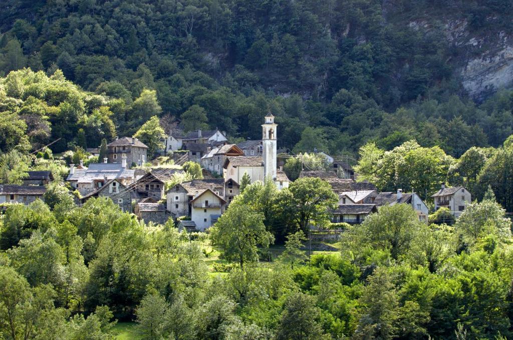 een klein dorpje in de bergen met een kerk bij Pensione Boschetto in Cevio