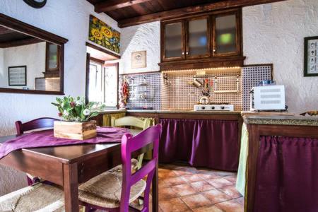 une cuisine avec une table en bois et des chaises violettes dans l'établissement Casa Gisira, à Catane