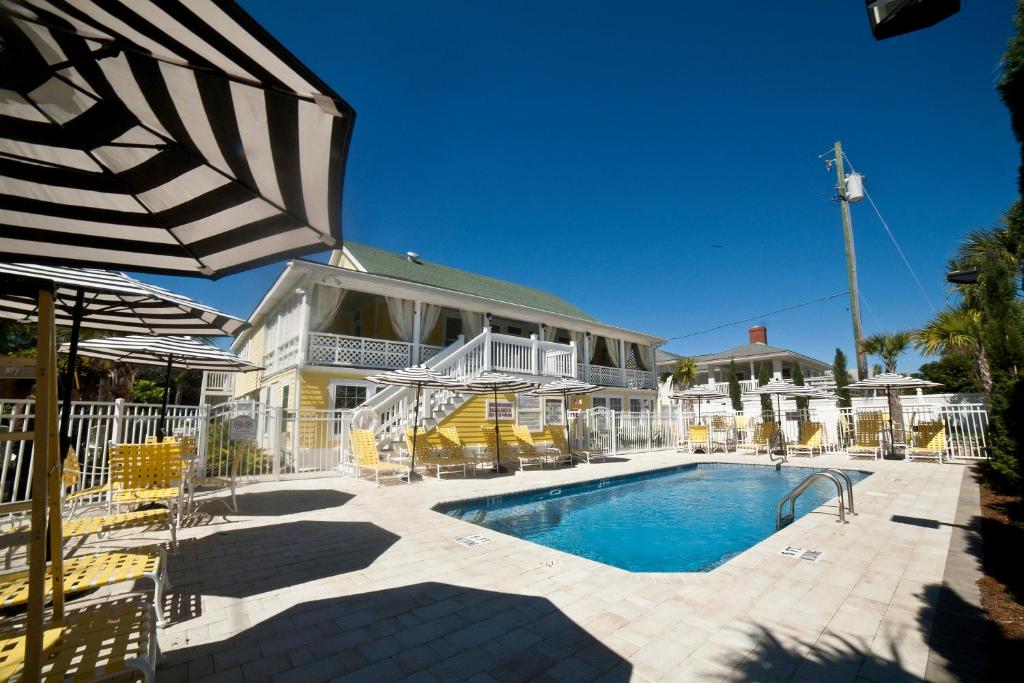 a pool with chairs and an umbrella in front of a house at Georgianne Inn & Suites check in 212 Bulter Ave in Tybee Island