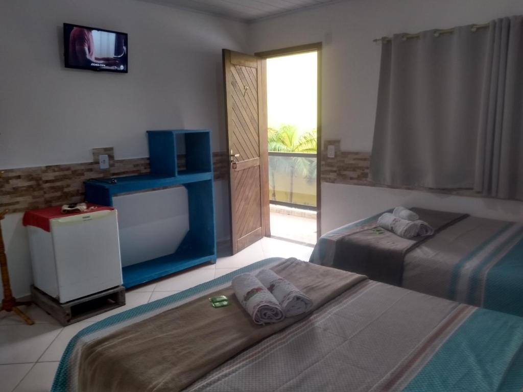 a hotel room with two beds and a television at Pousada Vó Nita in Penha
