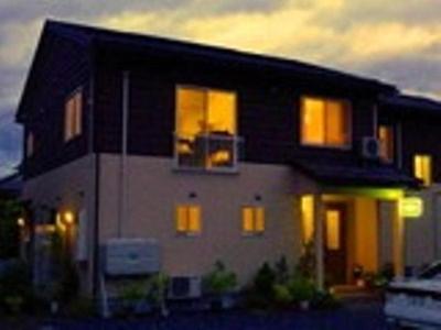 a black and white house with its lights on at Guesthouse Mintaro Hut in Yamagata