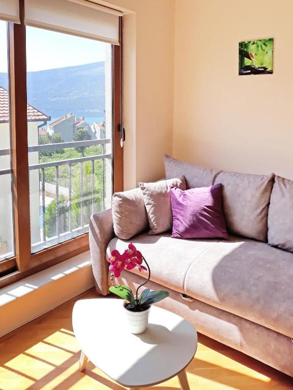 a living room with a couch and a large window at Lila apartmani in Baošići