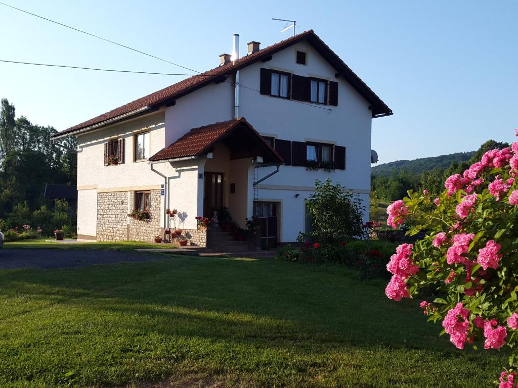 una casa blanca con jardín y flores en Apartments Jure, en Smoljanac