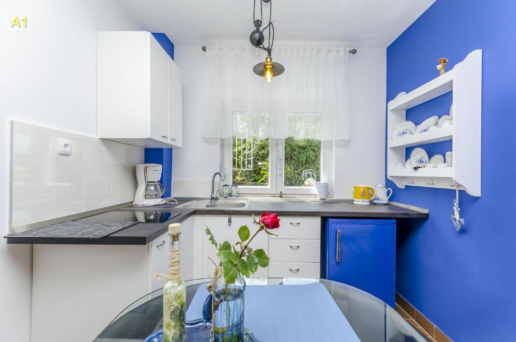 cocina azul y blanca con mesa de cristal en Apartments Marin, en Rogoznica