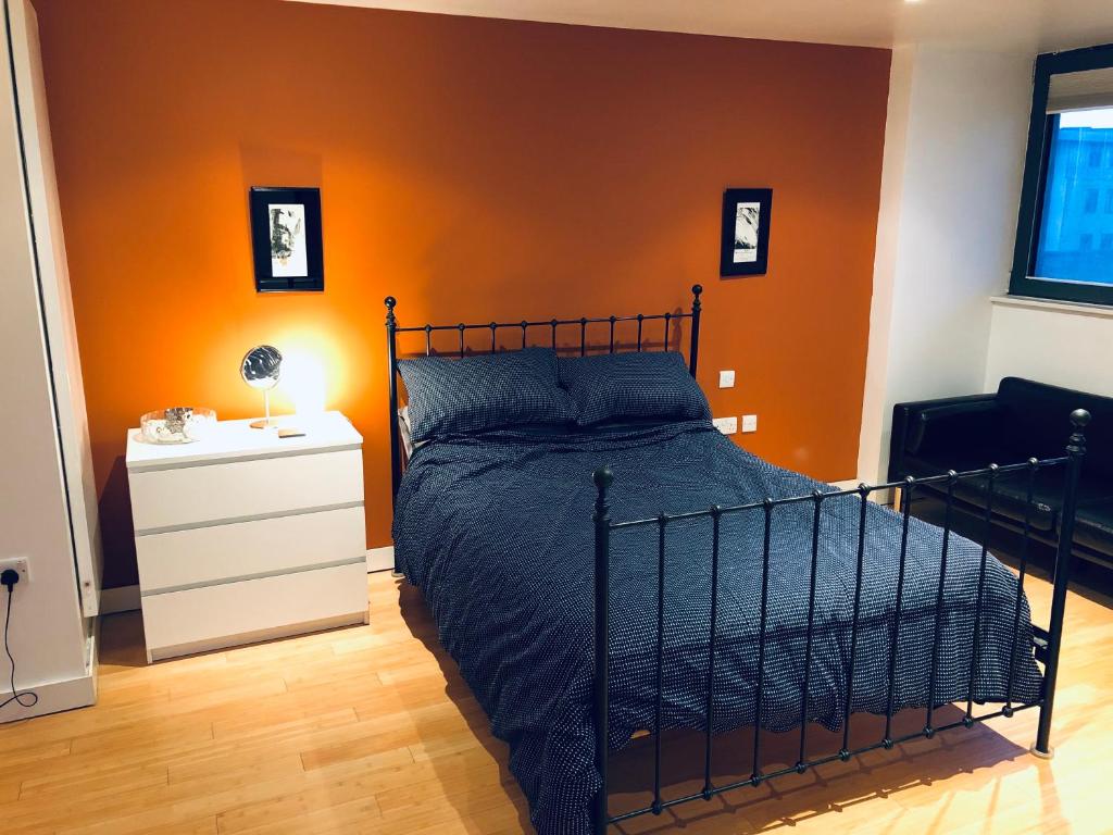 a bedroom with a bed and an orange wall at Designer Room with Private Bathroom in London