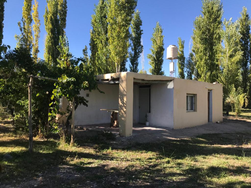 a small white building in a field with trees at Maju in Calingasta