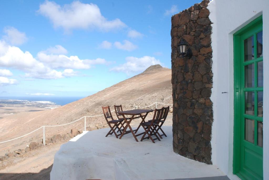 una mesa y sillas en un balcón con una montaña en Villa El Perinqué, en Femés
