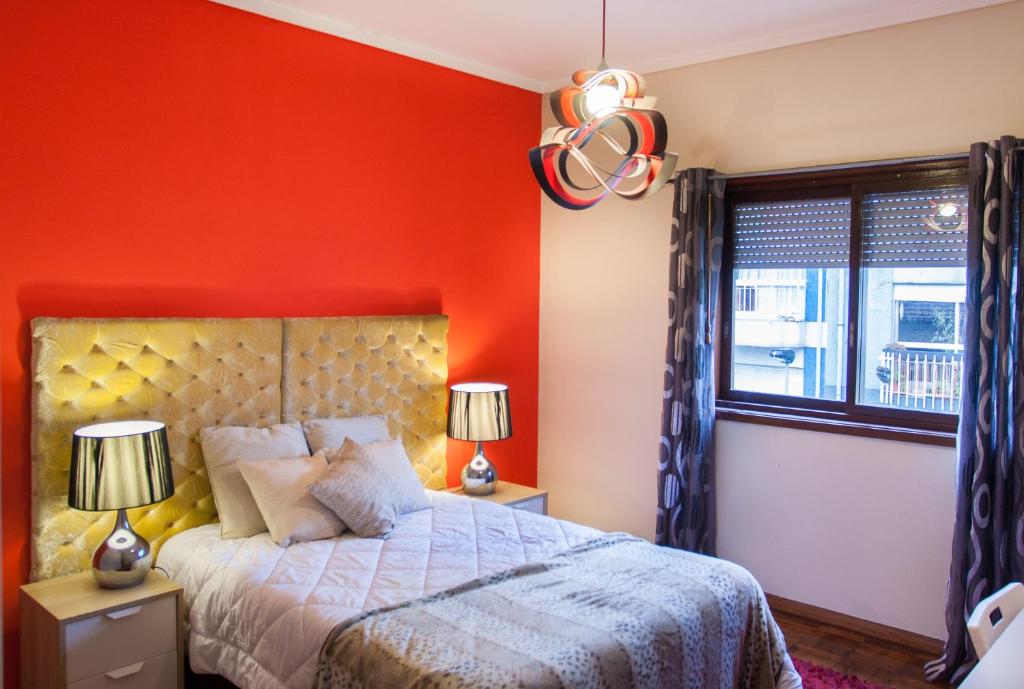 a bedroom with an orange wall and a bed at Oporto Cozy Rooms in Porto