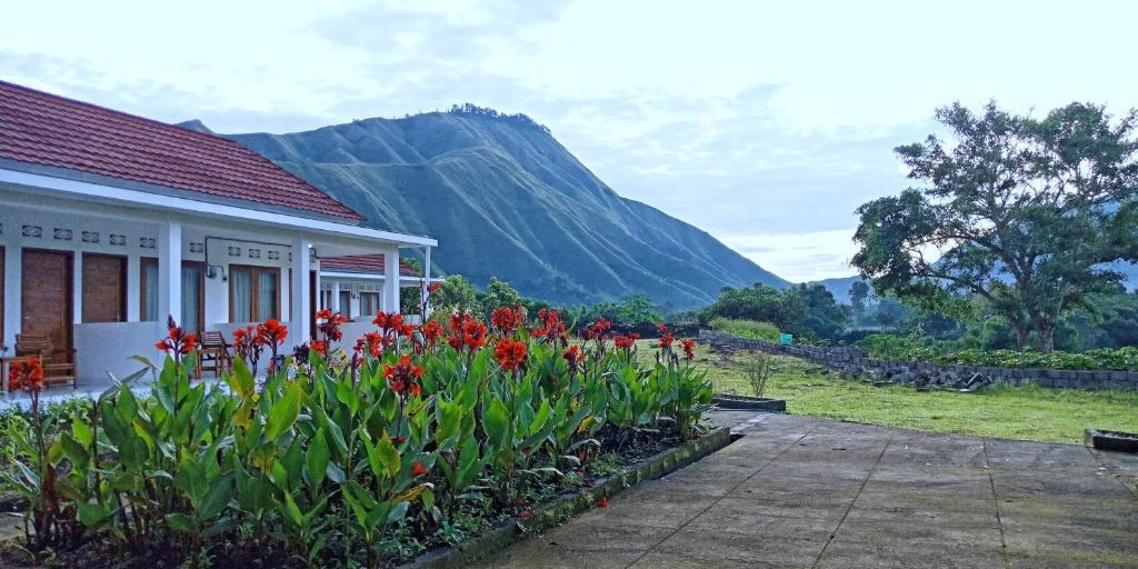 a house with flowers in front of a mountain at Rinjani Hill Hotel in Sembalun Lawang