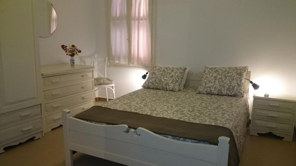 a bedroom with a white bed and a dresser at Casa Patrikò in Perivólia